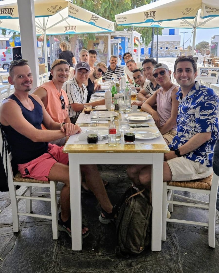The group round one long table at lunch, under the umbrellas
