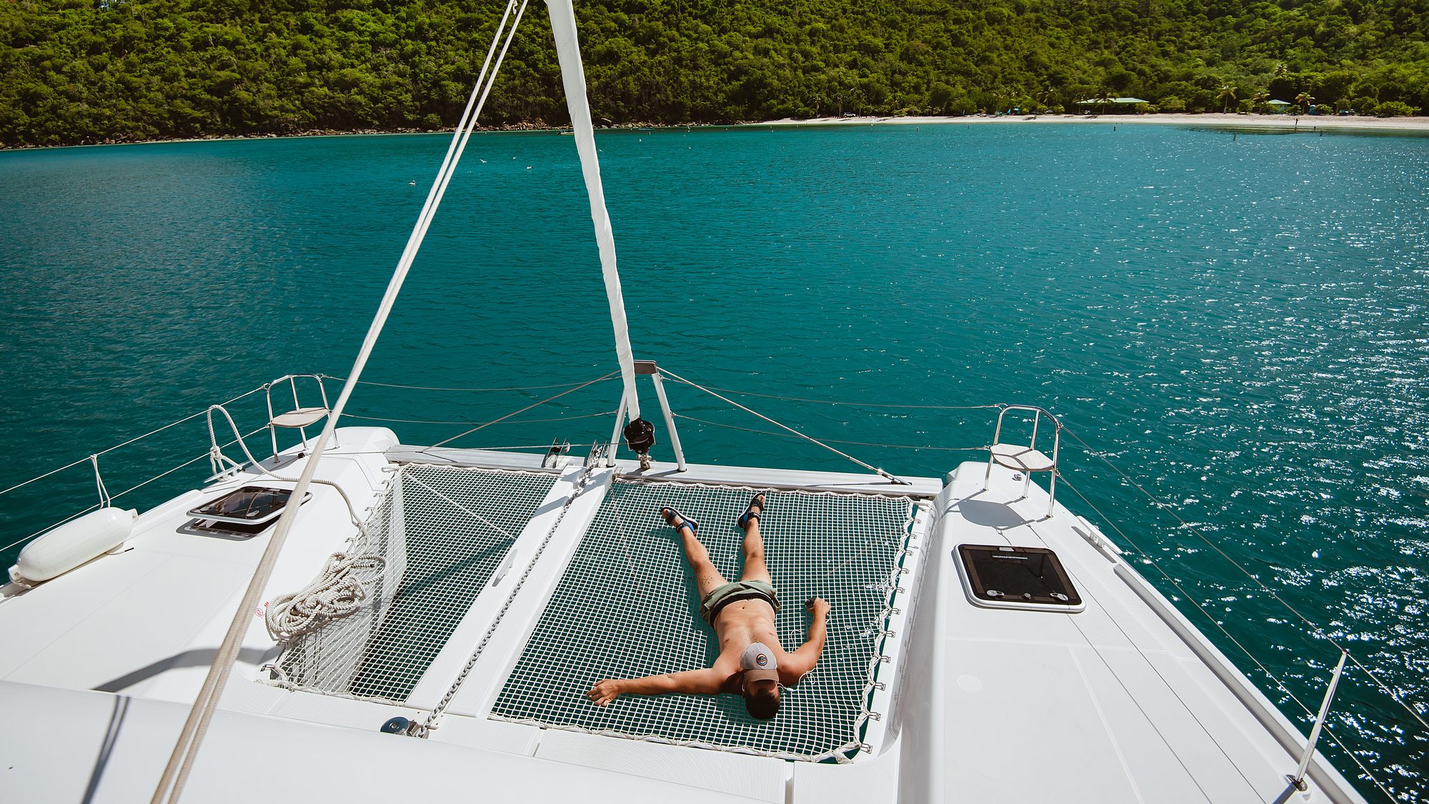 Lying out on the trampoline of the catamaran over turquoise water