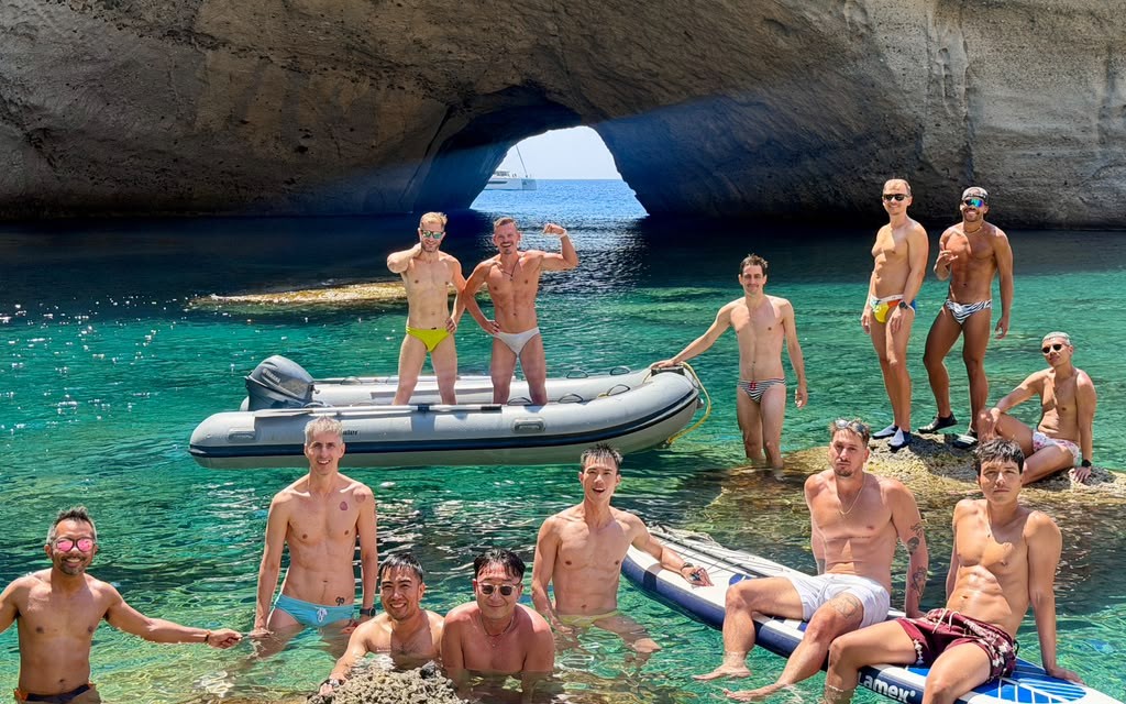 The group in a sea cave with the catamaran framed in the arch beyond