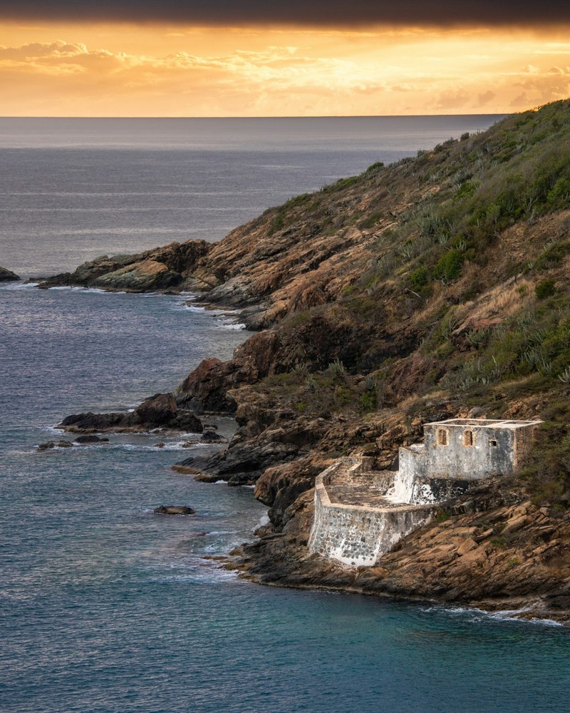 Old stone ruins on a headland above the water at sunset
