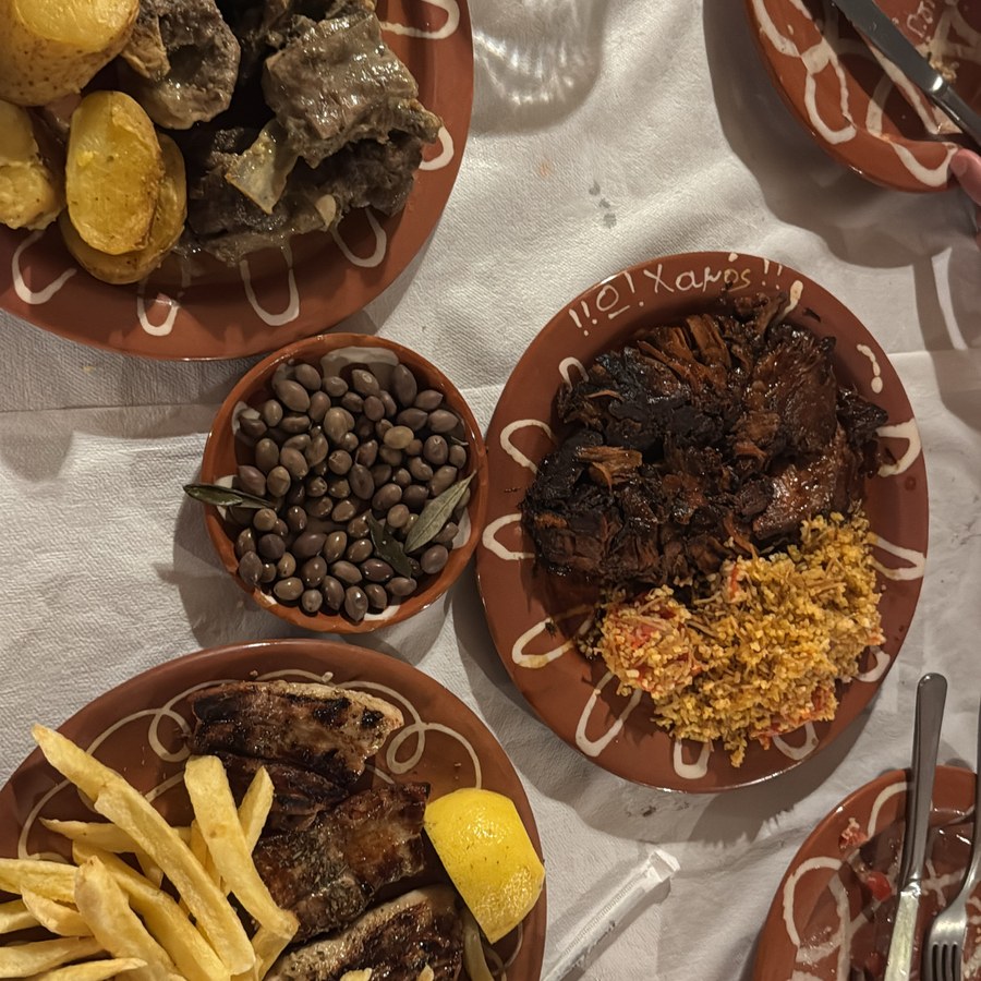 A table spread of grilled food, potatoes, and olives