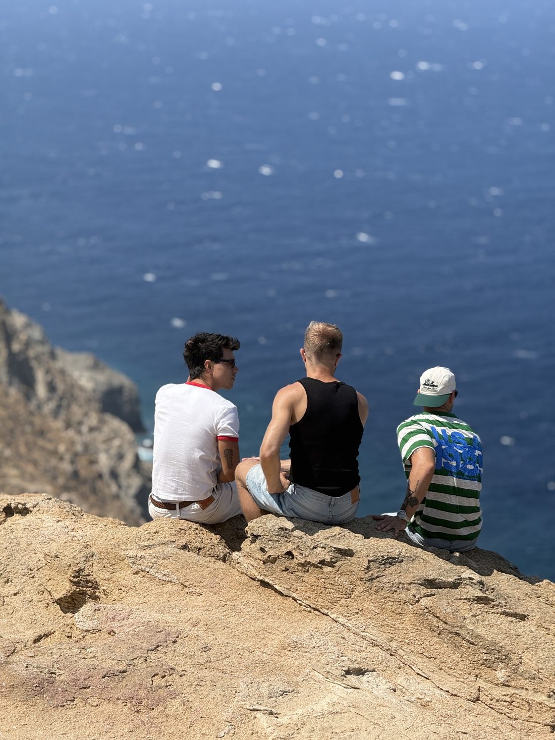Three of the group sitting on a rock above the sea